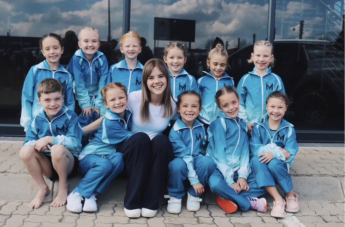 iMove team in aqua tracksuits with their coach at a competition