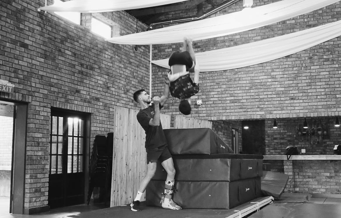 Coach spotting a gymnast through an inverted skill in the gym
